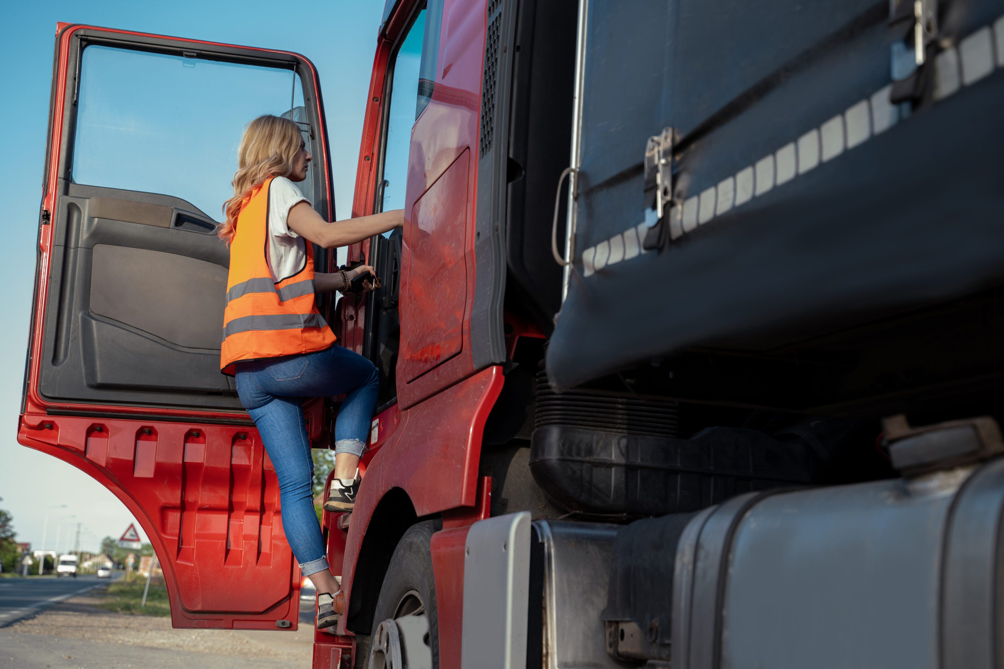 Woman climbing into a red truck.